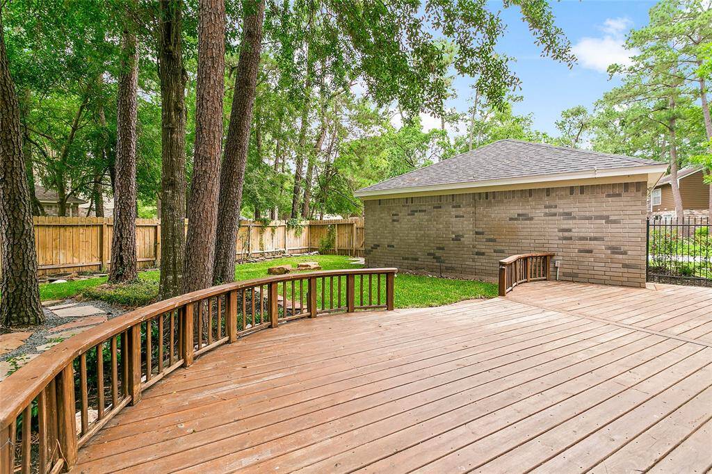 Enjoy relaxing on this large wooden deck, ideally situated next to the brick garage and offering views of the tree-shaded, fenced backyard.
