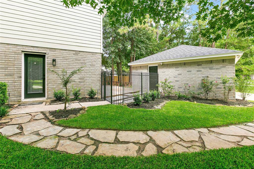 Well-designed outdoor flow featuring a prominent stone walkway that connects the kitchen entrance, tidy lawn, and detached garage.