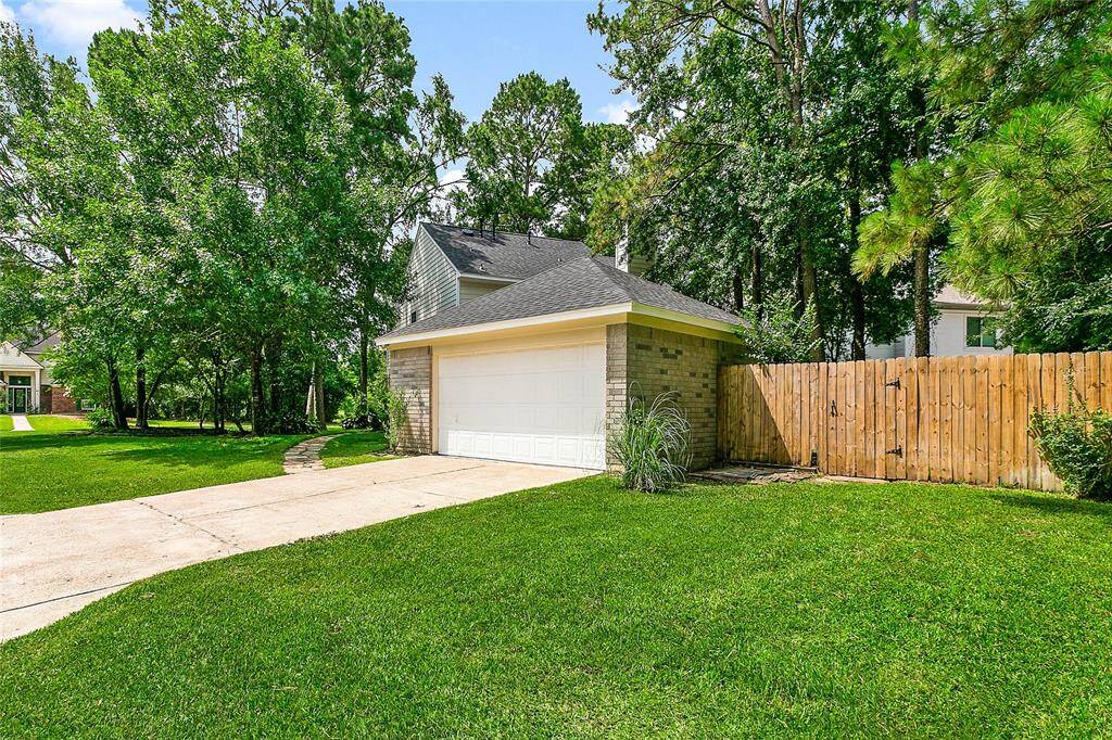 Substantial detached garage with a wide driveway offers ample parking and easy access. Features a beautifully maintained lawn, tall wooden privacy fence, and a mature, tree-lined setting.