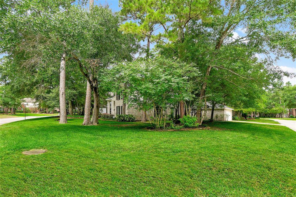 This property features an expansive, park-like front lawn where abundant mature shade trees create a naturally private setting for the home.