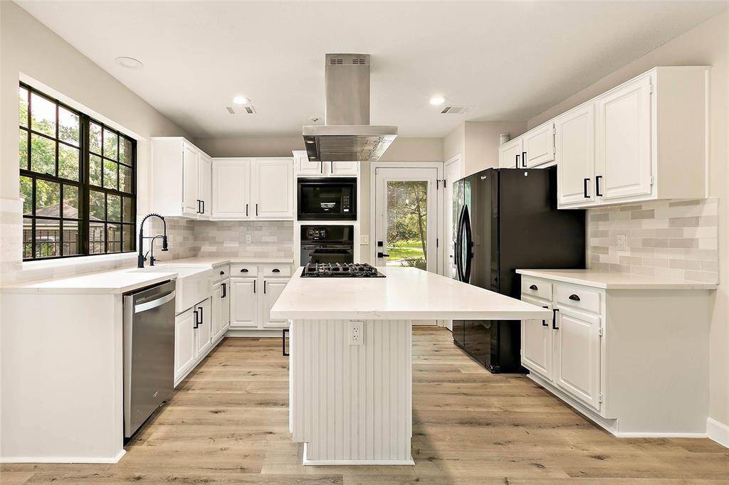Open-concept kitchen featuring quartz countertops, gorgeous backsplash, and a large island with bar seating.