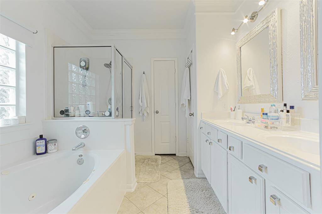 En suite bath with double sinks and separate shower and tub.
