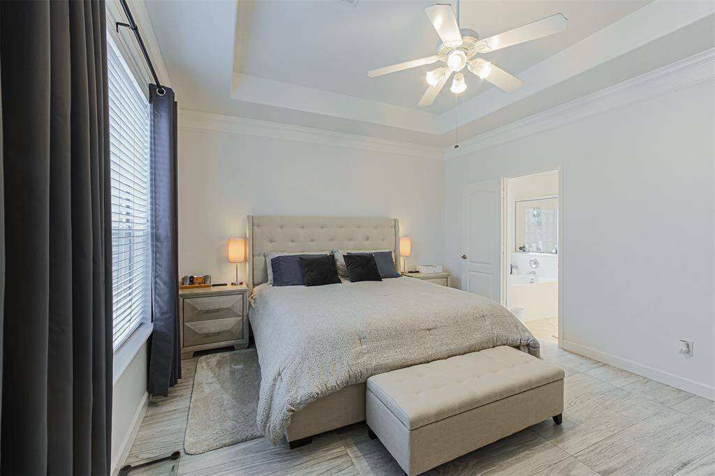Primary bedroom located on the first floor with tray ceiling and view of the backyard.