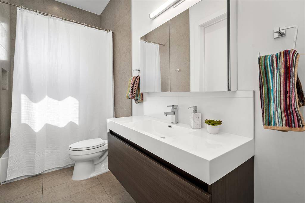 Secondary bathroom featuring an expansive vanity that offers plenty of storage. Bathroom includes a window, but situated in a way that keeps it very private