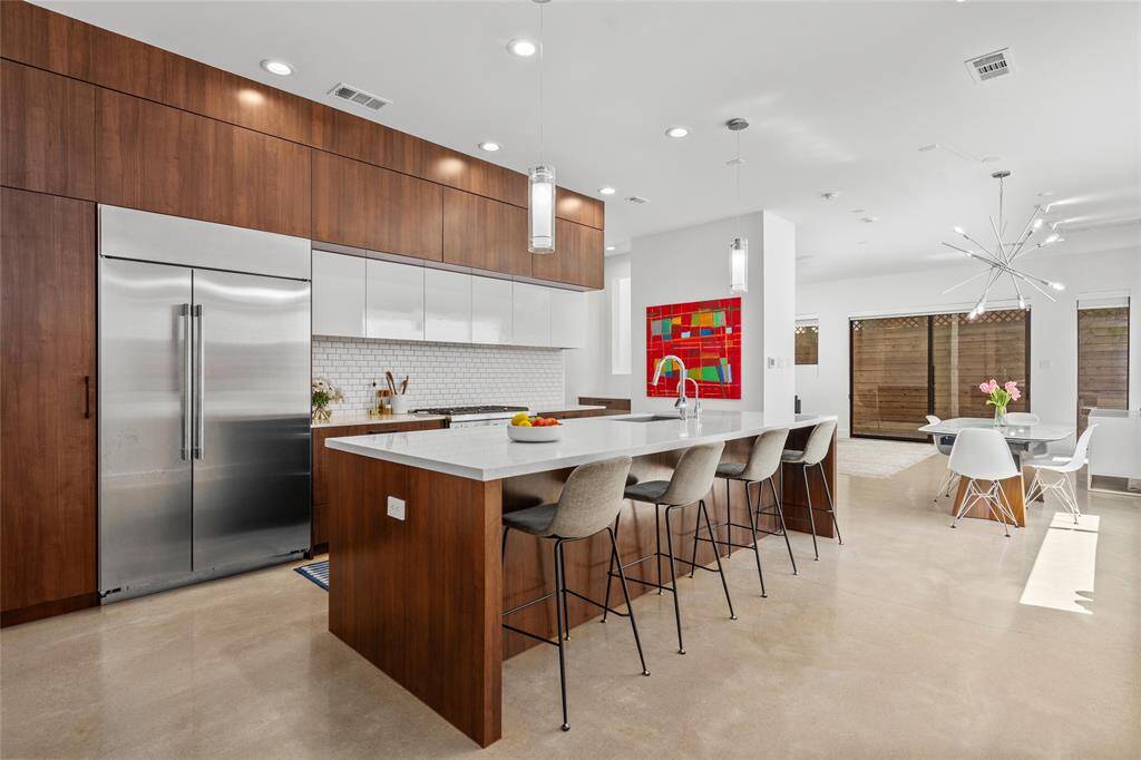 The kitchen has many impressive features, including a spacious walk-in pantry, ideal for storing extra appliances, a high-end GE Monogram refrigerator, and ample storage in sleek, soft-close cabinetry.
