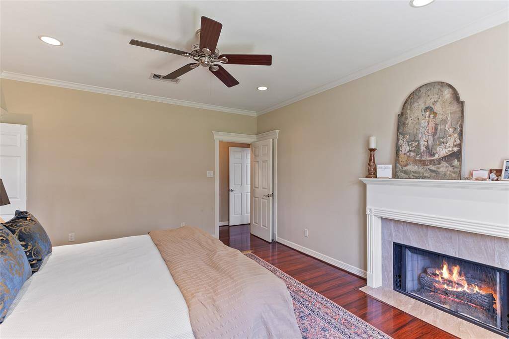 Serene primary bedroom featuring a cozy gas fireplace & laminate wood flooring, replacing the original carpet to create a seamless, cohesive flow with the rest of the downstairs living spaces.