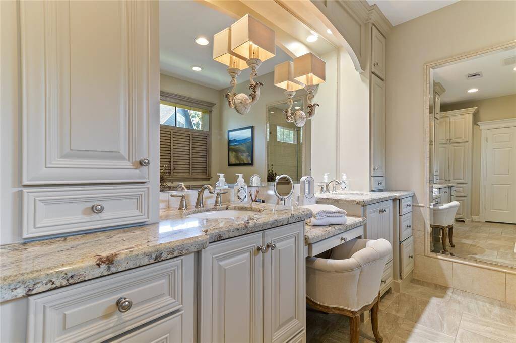 This elegant primary bathroom vanity was thoughtfully designed & custom built to perfectly complement the space—featuring abundant storage, beautiful granite countertops & a dedicated makeup station for everyday luxury.