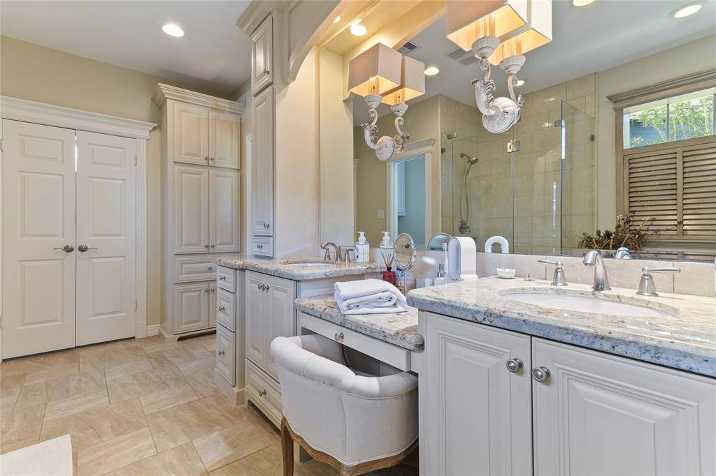 This beautifully designed primary bathroom offers an impressive amount of built-in cabinetry for seamless storage, along with a spacious 9x7 walk-in closet—tucked behind the double doors—featuring custom shelving and organization.