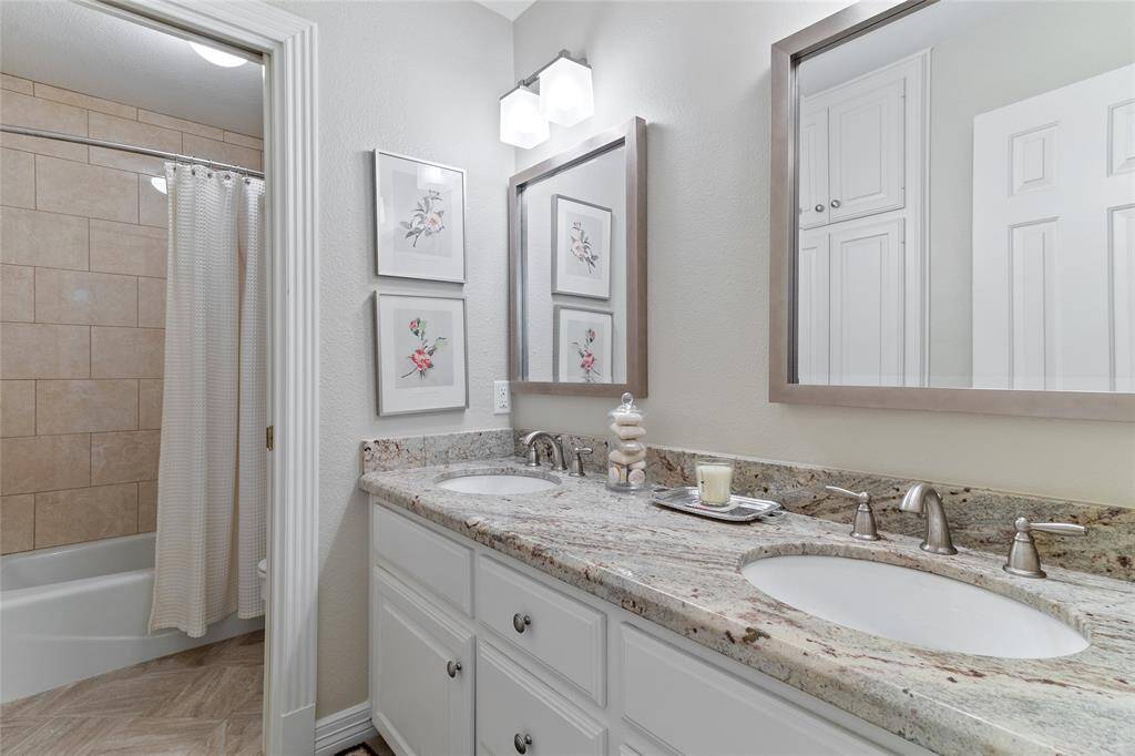 Located upstairs between the two secondary bedrooms, this updated full bathroom features granite countertops with dual sinks & a tiled tub/shower combo—offering both function & convenience for guests or family.