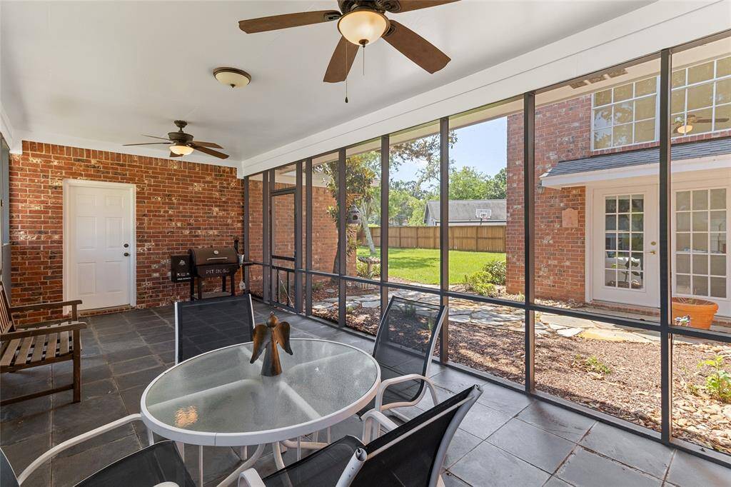 The expansive screened-in patio is the perfect space for relaxing or entertaining with durable slate tile flooring, dual ceiling fans & easy access to both the backyard & driveway for seamless indoor-outdoor living.