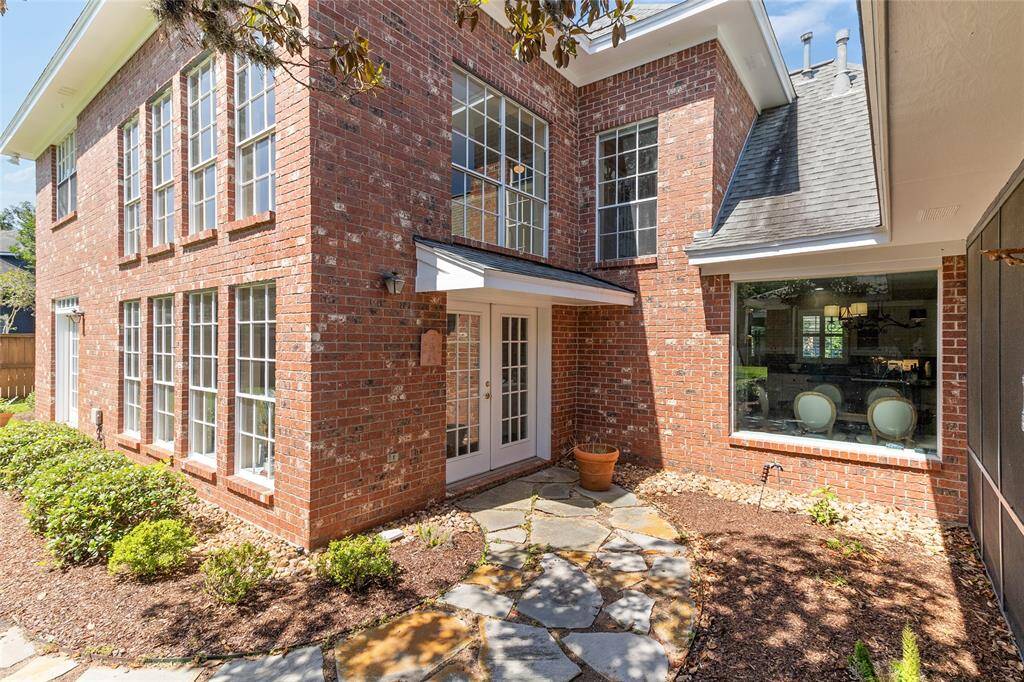 This picturesque courtyard highlights recent improvements, including a roof covering installed over the French doors in 2021 for added weather protection & freshly re-caulked family room windows completed in 2024 to improve energy efficiency & maintain a polished finish.