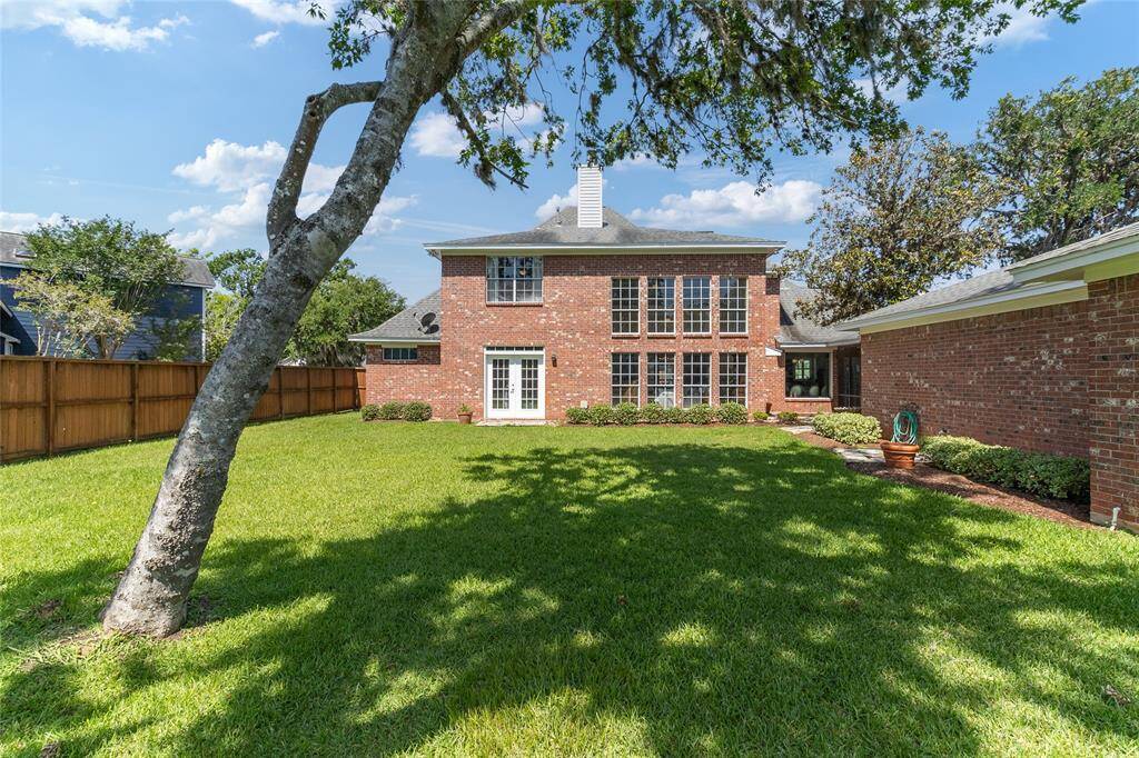 Stunning rear view of the home highlighting its classic brick exterior & lush backyard, with added confidence from foundation repairs completed in 2013—backed by a lifetime transferrable warranty.
