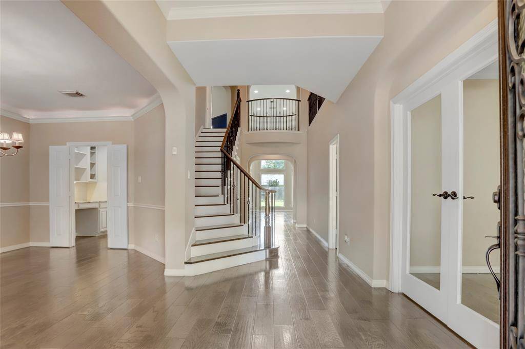 Step inside to a grand foyer with soaring ceilings, crown molding, and rich wood floors that set the tone for the home's spacious layout.