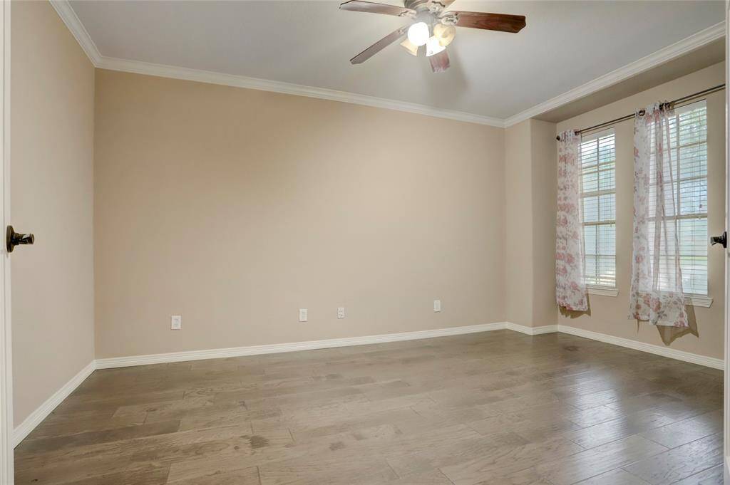 This private study features a ceiling fan, corner windows, and beautiful wood flooring—ideal for remote work or quiet reading.