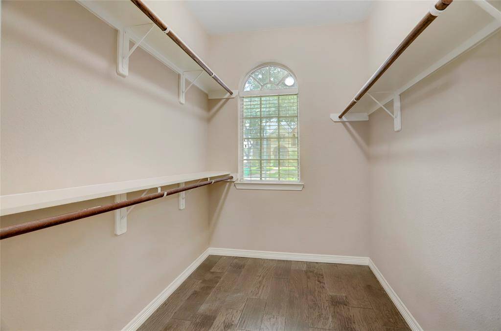 The primary suite's walk-in closet features custom built-ins and a window for natural lighting.