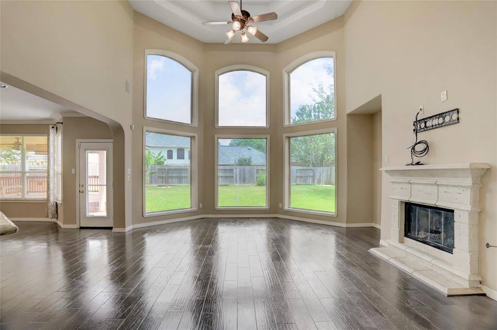 The spacious family room features a gaslog fireplace, soaring ceilings, and floor-to-ceiling windows offering serene backyard views.