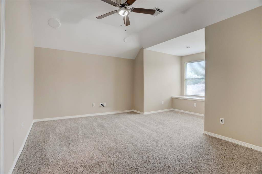 Another secondary bedroom offers a spacious layout, ceiling fan, and large windows.