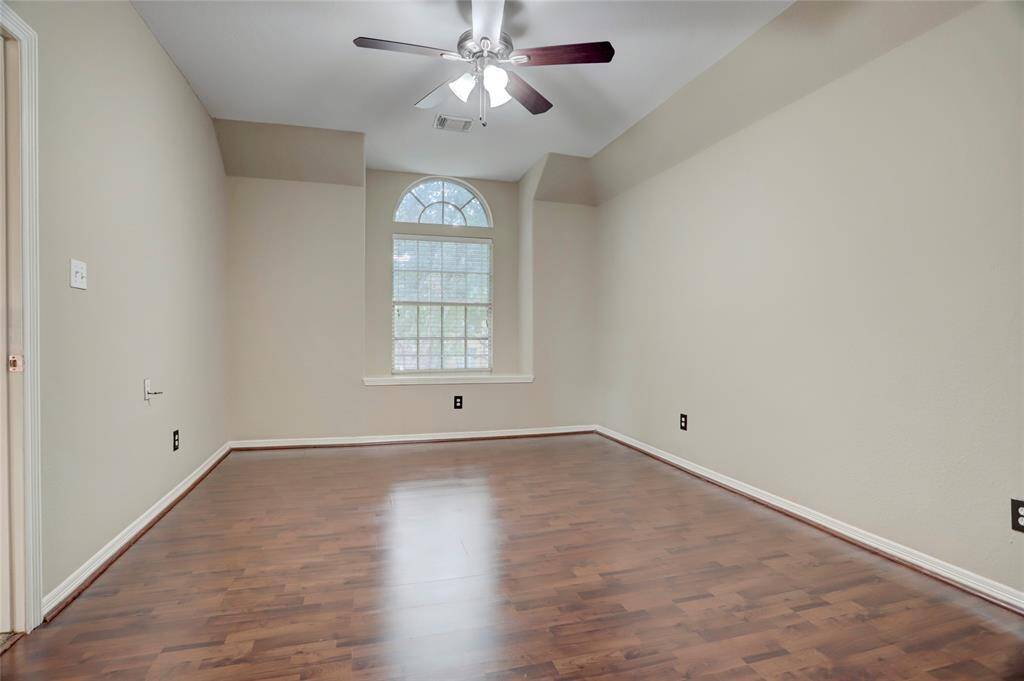 This bedroom includes wood flooring and arched window design, adding unique character.