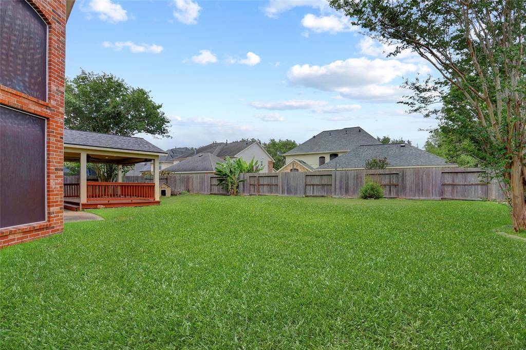 A final view of the backyard highlights its expansive layout and the home's brick exterior from behind.