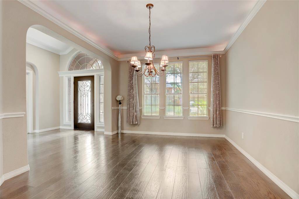 The formal dining room highlights wainscoting, elegant lighting, and direct access to the foyer for easy entertaining.