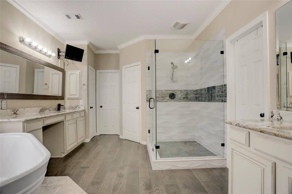 The primary bath includes dual vanities, a walk-in shower with frameless glass, soaking tub, and abundant storage.