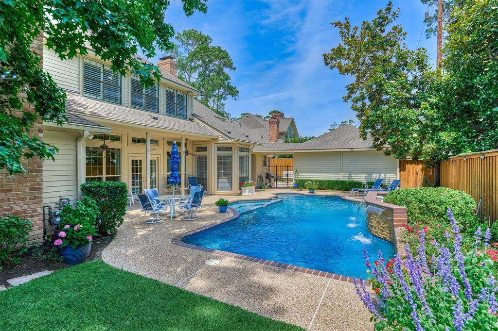 Backyard paradise with sparkling pool, water feature, lush landscaping, and spacious patio—perfect for entertaining or relaxing in style.