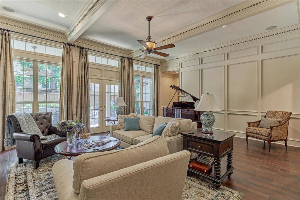 Wall of windows with transoms and French doors floods the living room with natural light and provides direct access to the backyard oasis.