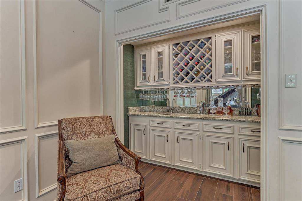 Custom wet bar with granite counters, wine storage, glass display cabinets, and a mirrored backsplash—ideal for entertaining with elegance.