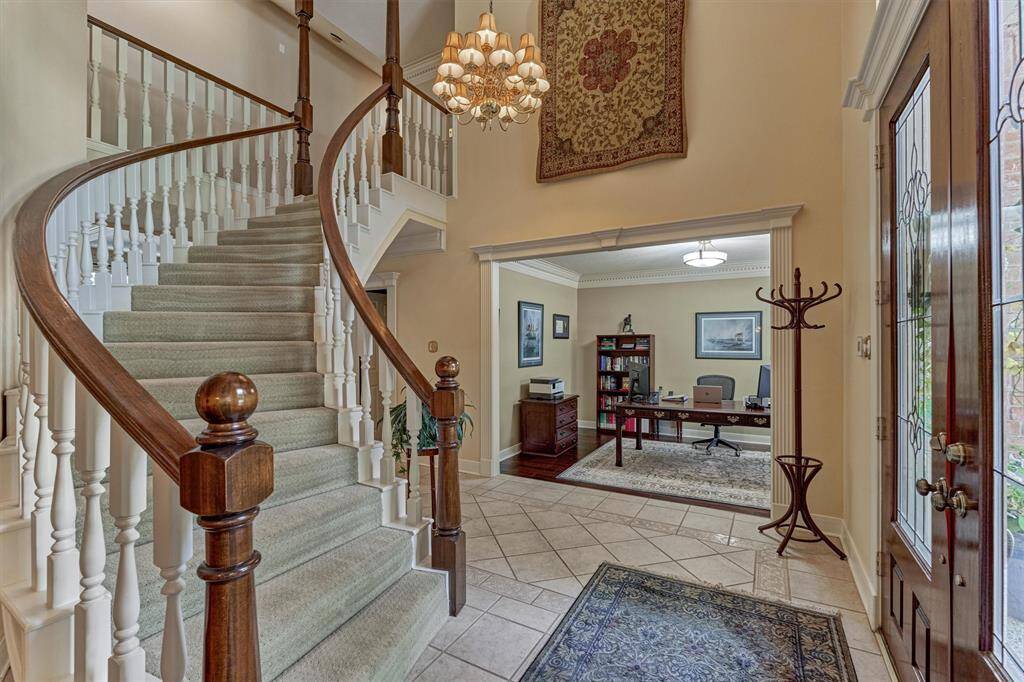 Stunning entryway with soaring ceilings, curved staircase, and a view into the spacious front office—welcoming and functional from the moment you walk in.