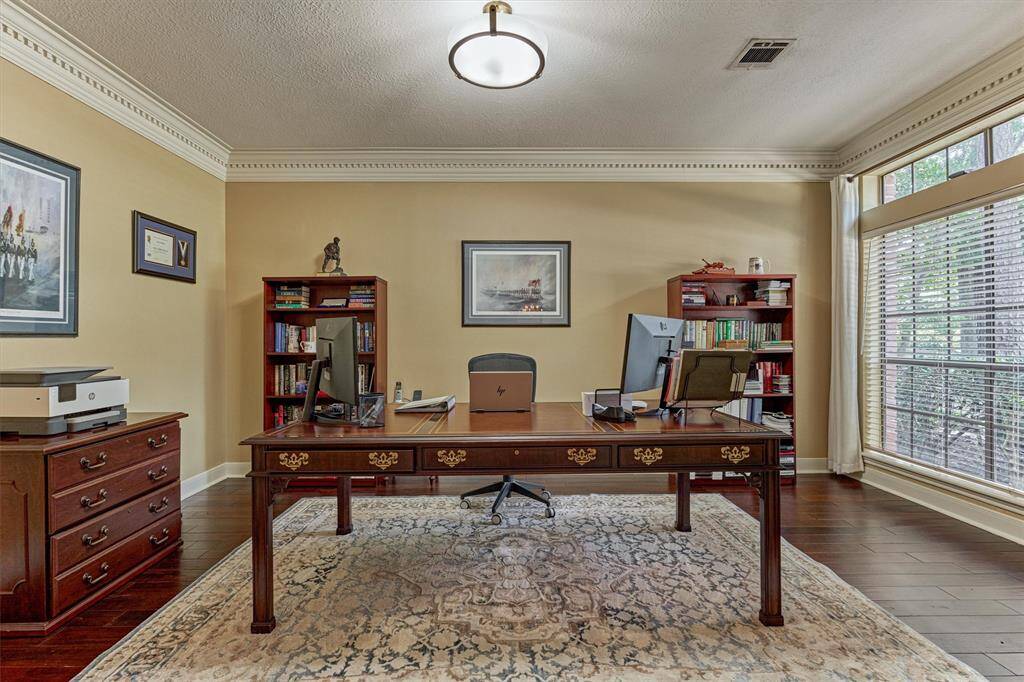 Private study with rich flooring, crown molding, and a large window offering natural light—ideal for working from home.