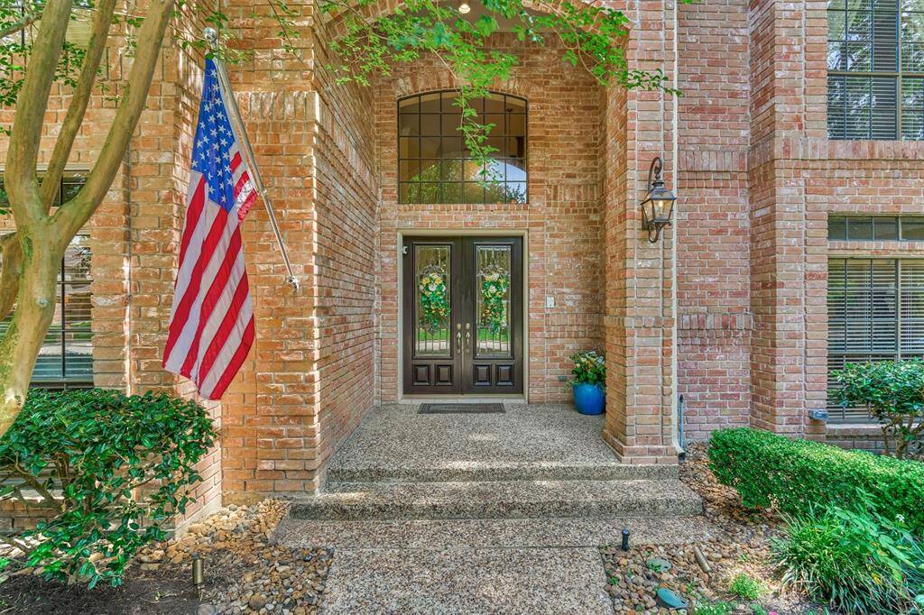 Inviting front entrance with double leaded-glass doors, brick archway, and detailed landscaping for stunning curbside appeal.
