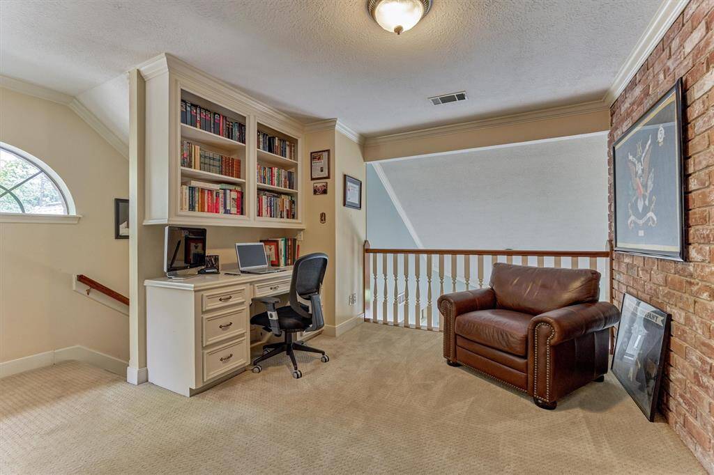 A charming built-in desk and bookshelves make this upstairs landing the perfect office nook or cozy reading corner—complete with views overlooking the elegant entryway.