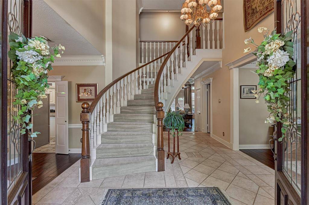 Grand two-story entryway with elegant curved staircase, tile flooring, and soaring ceilings—an impressive welcome for every guest.