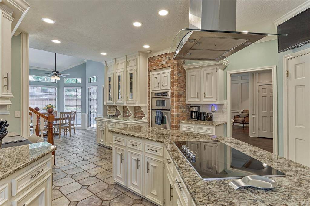 View toward the cozy breakfast nook and built-in cabinetry, showcasing extensive storage, double ovens, and open layout into living spaces.