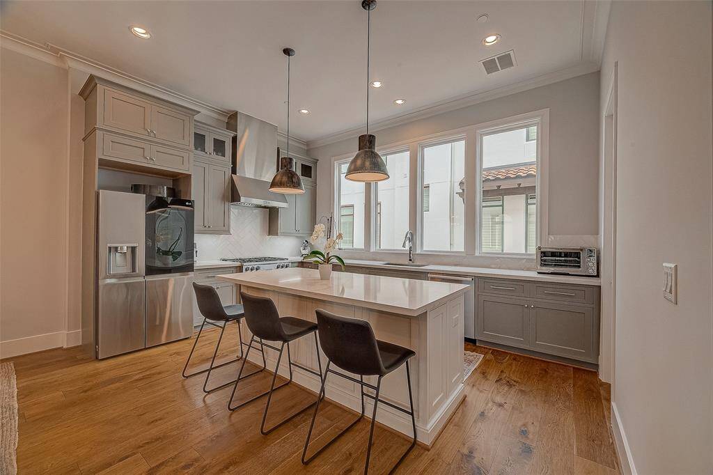 Island kitchen features Miele appliances, breakfast bar, quartz countertops, herringbone backsplash & ample storage.