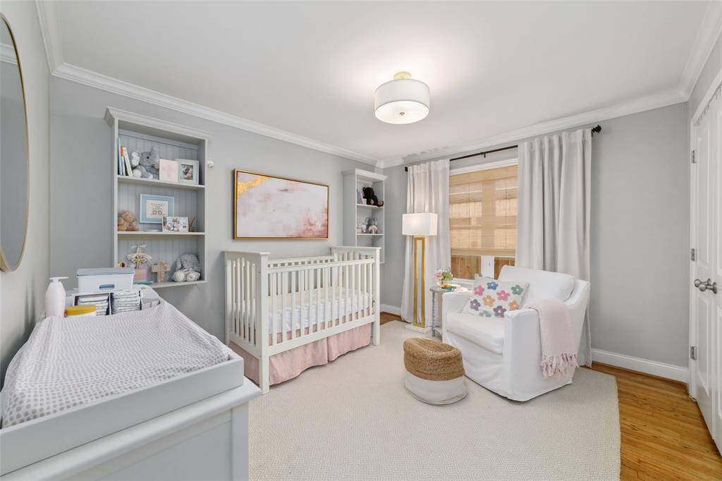 This serene guest bedroom is full of warmth and flexibility, with soft neutral tones, crown molding, and natural light filtering through the window. Whether used as a nursery, creative studio, or restful retreat, this space adapts to fit your needs.