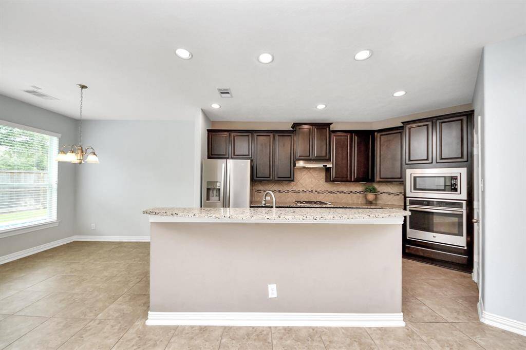 Breakfast bar could easily accommodate 4 bar stools and adds to seating in family room area, as well as the kitchen. Stainless appliances, gas cooktop, and French door style refrigerator stays.