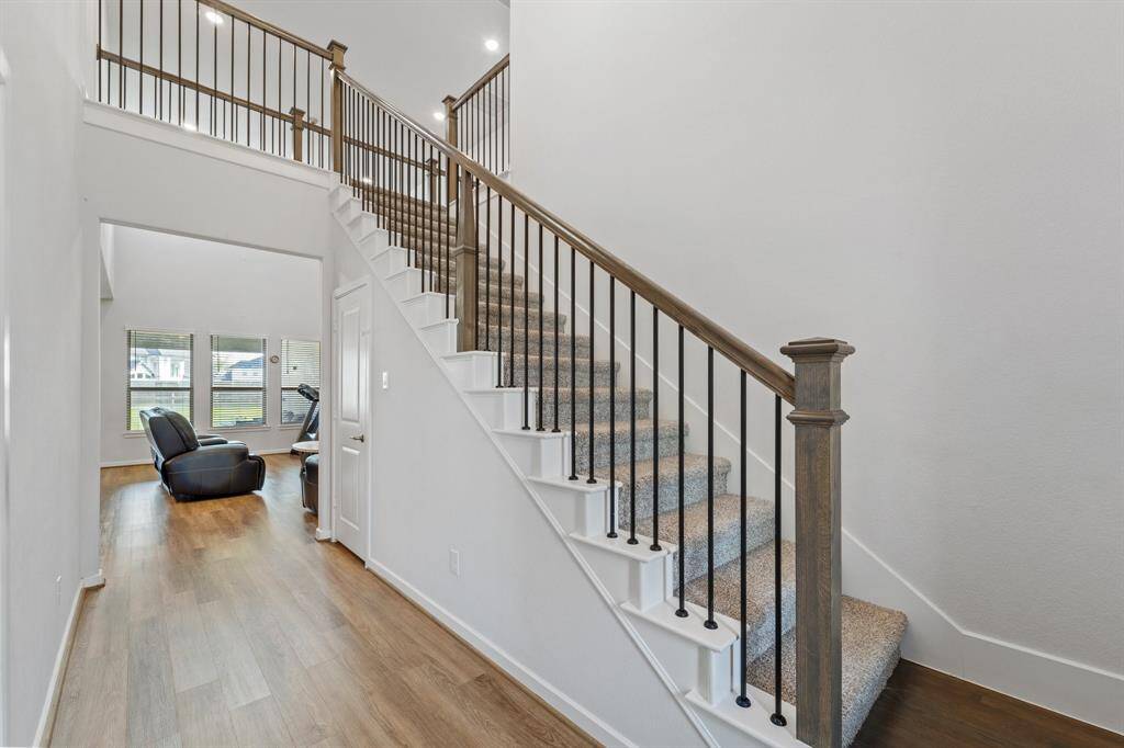 A welcoming entryway features fabulous floors and an elegant staircase with iron spindles, opening to the spacious living area filled with natural light.