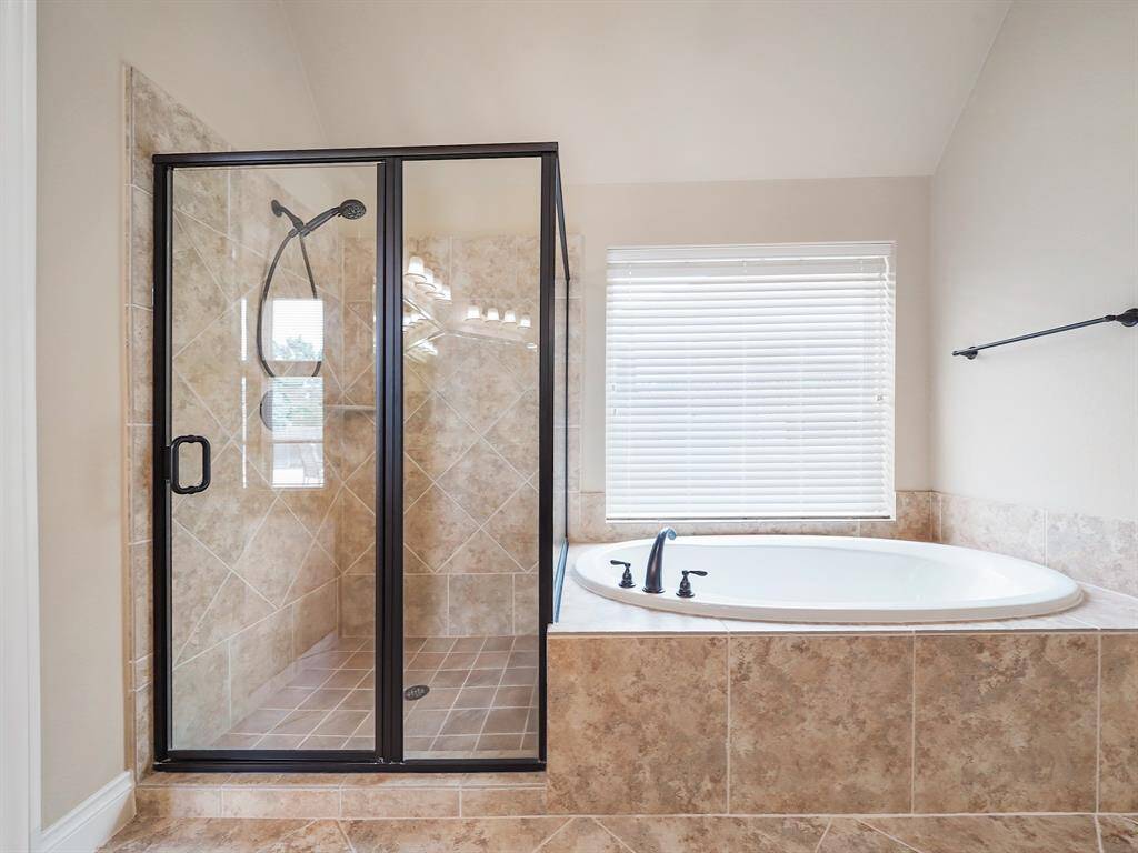 Indulge in ultimate relaxation in the luxurious ensuite, featuring a deep soaking tub perfectly positioned beneath a bright window. Unwind and rejuvenate in this spa-like oasis, complete with a separate tiled shower for added convenience and style.