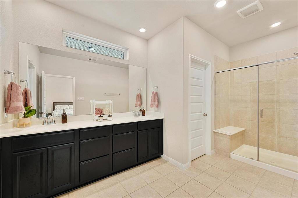 Luxurious bathroom featuring double vanity, and a walk-in shower with elegant tile finishes.