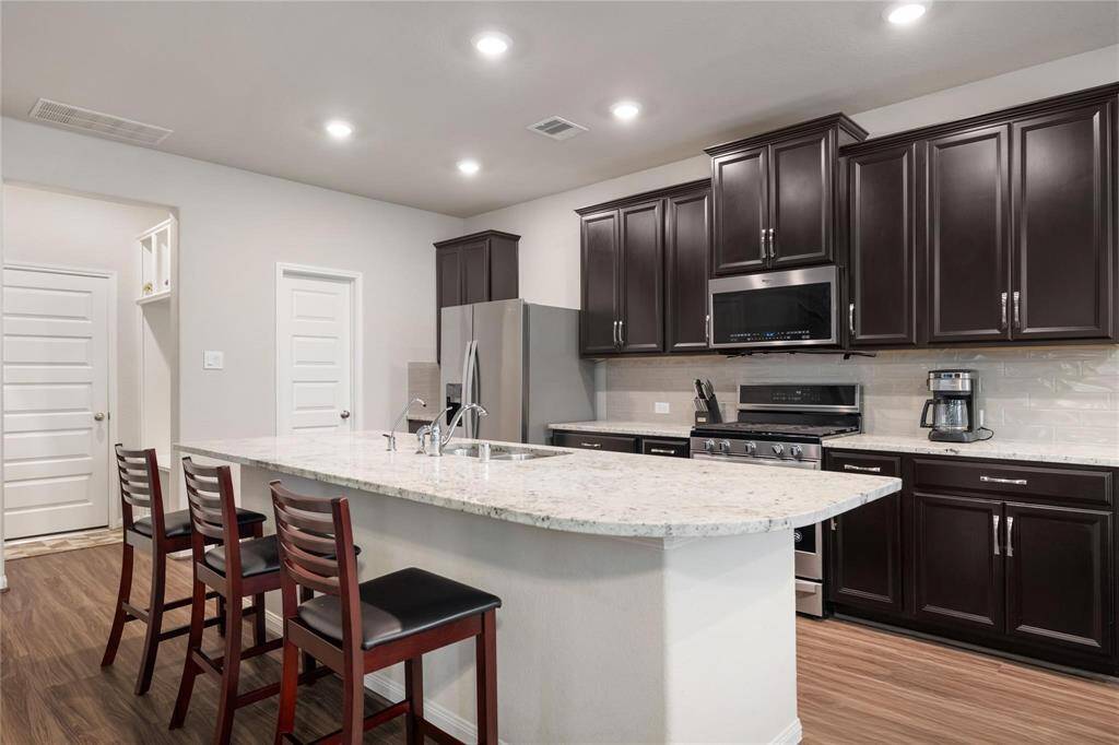 Open-concept living and dining area with rich wood flooring and large windows allowing natural light to flow in.