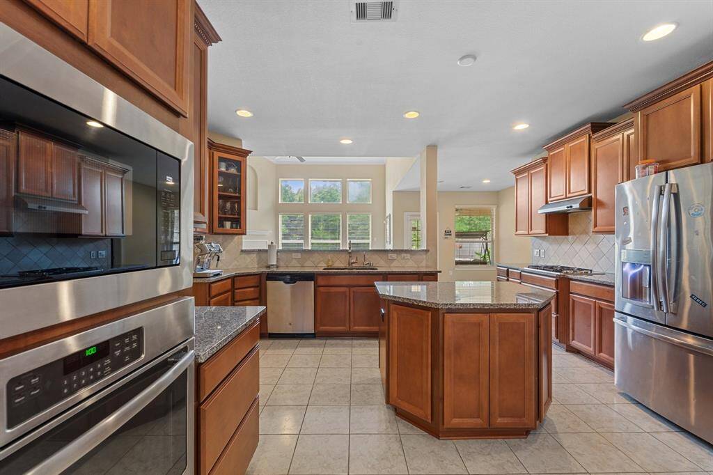 Enjoy views of the backyard and living room while working at the sink in this thoughtfully designed kitchen featuring granite counters and stainless steel finishes.