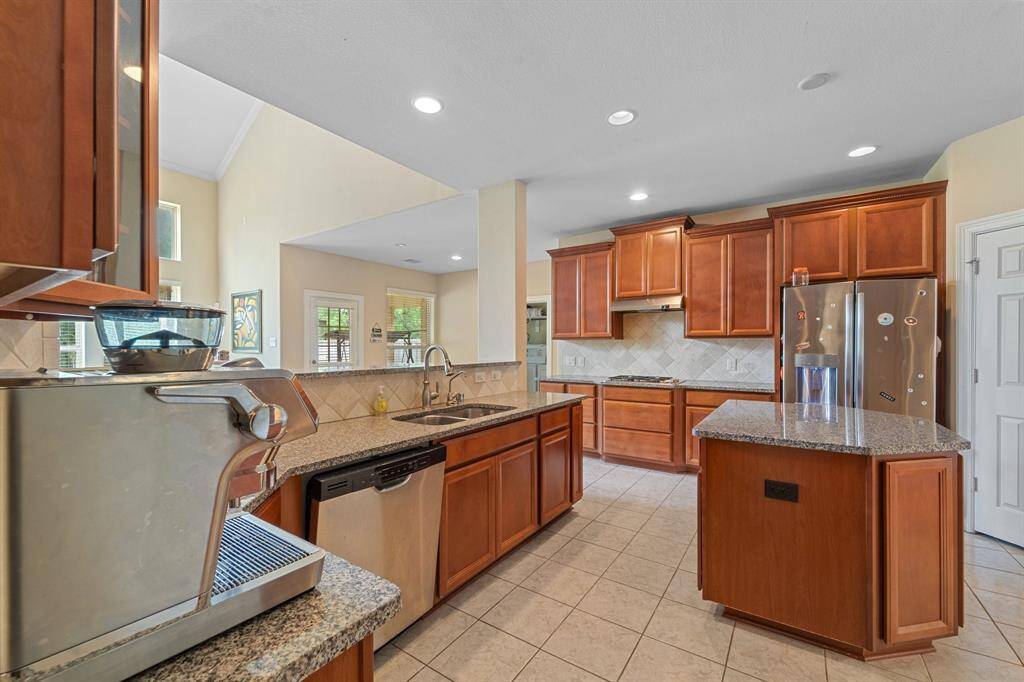 Open-concept kitchen offers abundant cabinet storage, stainless steel appliances, and a large island overlooking the living area.