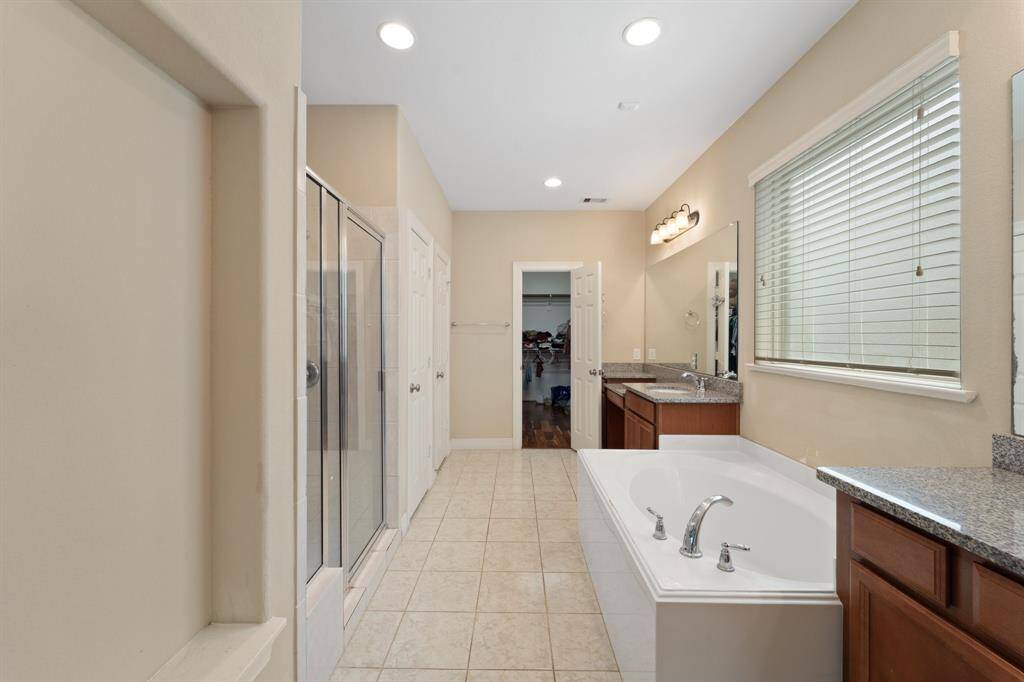 The luxurious primary bathroom is complete with separate vanities, a soaking tub, walk-in shower, and access to the closet—perfectly designed for comfort and functionality.
