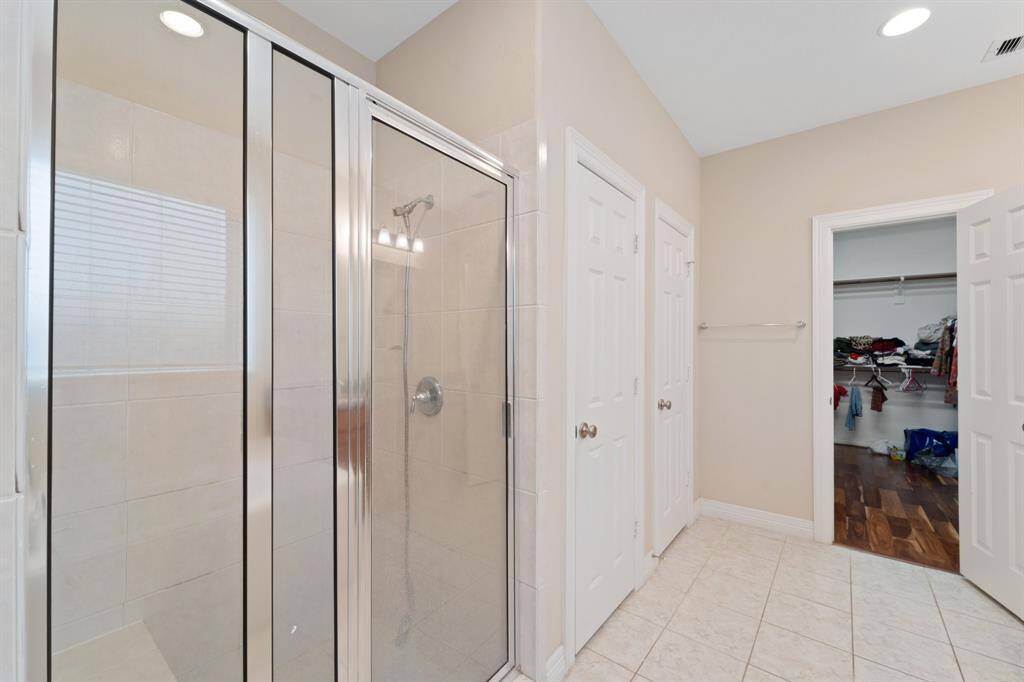 Walk-in shower with tile surround is positioned near the private water closet and linen closet and is located across from the oversized walk-in wardrobe.