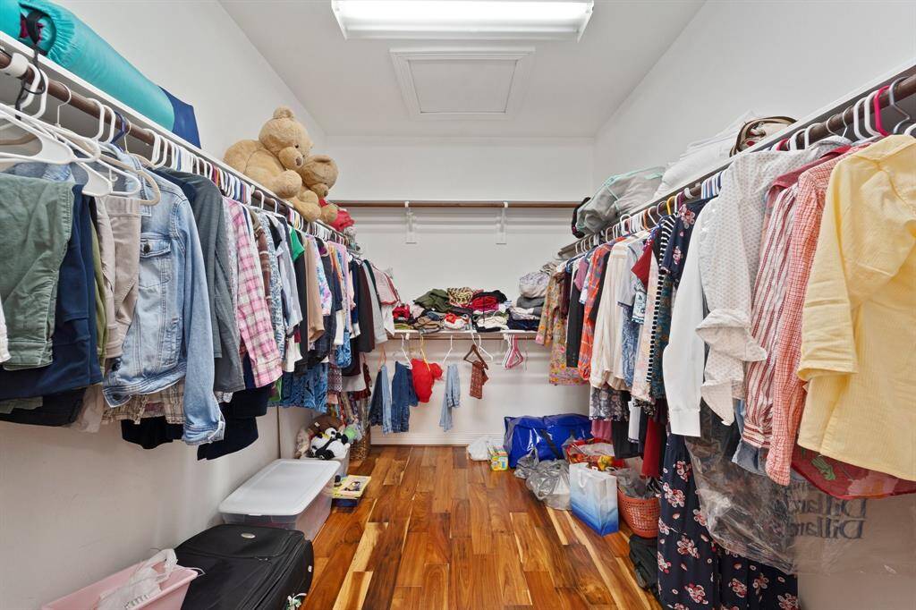 Massive walk-in closet with wood floors offers abundant storage and built-in hanging space along both walls.