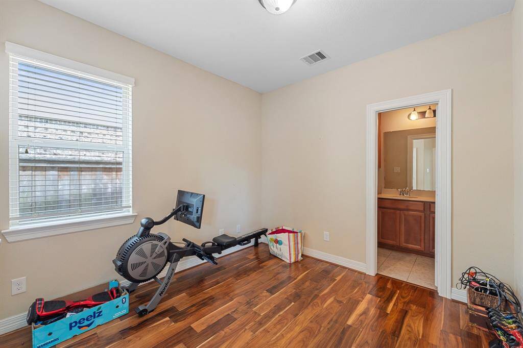 This versatile main floor bedroom features wood flooring, a large window for natural light, and convenient access to an ensuite full bathroom.