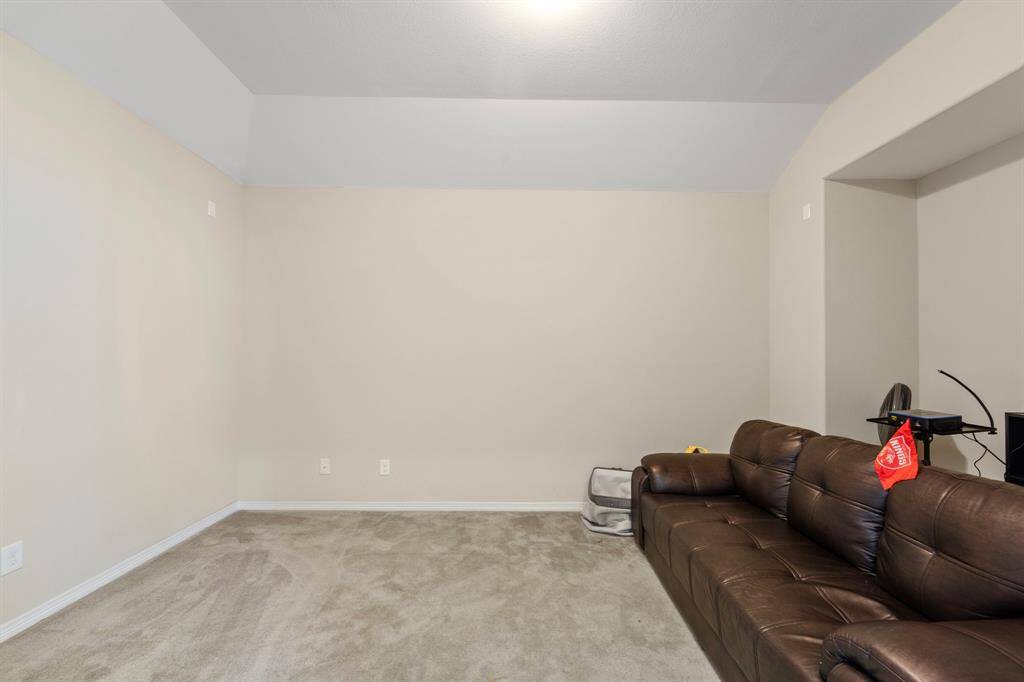 Spacious media room with plush carpet, high ceilings, and a recessed wall perfect for a projector or entertainment setup.