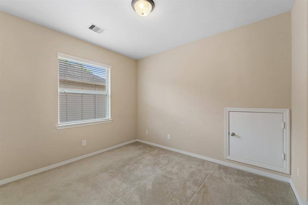 Light-filled bedroom with plush carpeting and a discreet hidden storage door for added convenience.
