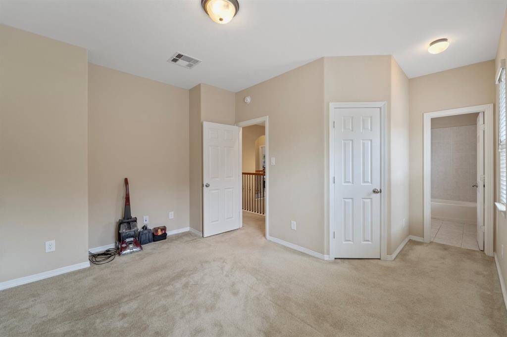 Spacious upstairs bedroom includes private ensuite bath access and walk-in closet.